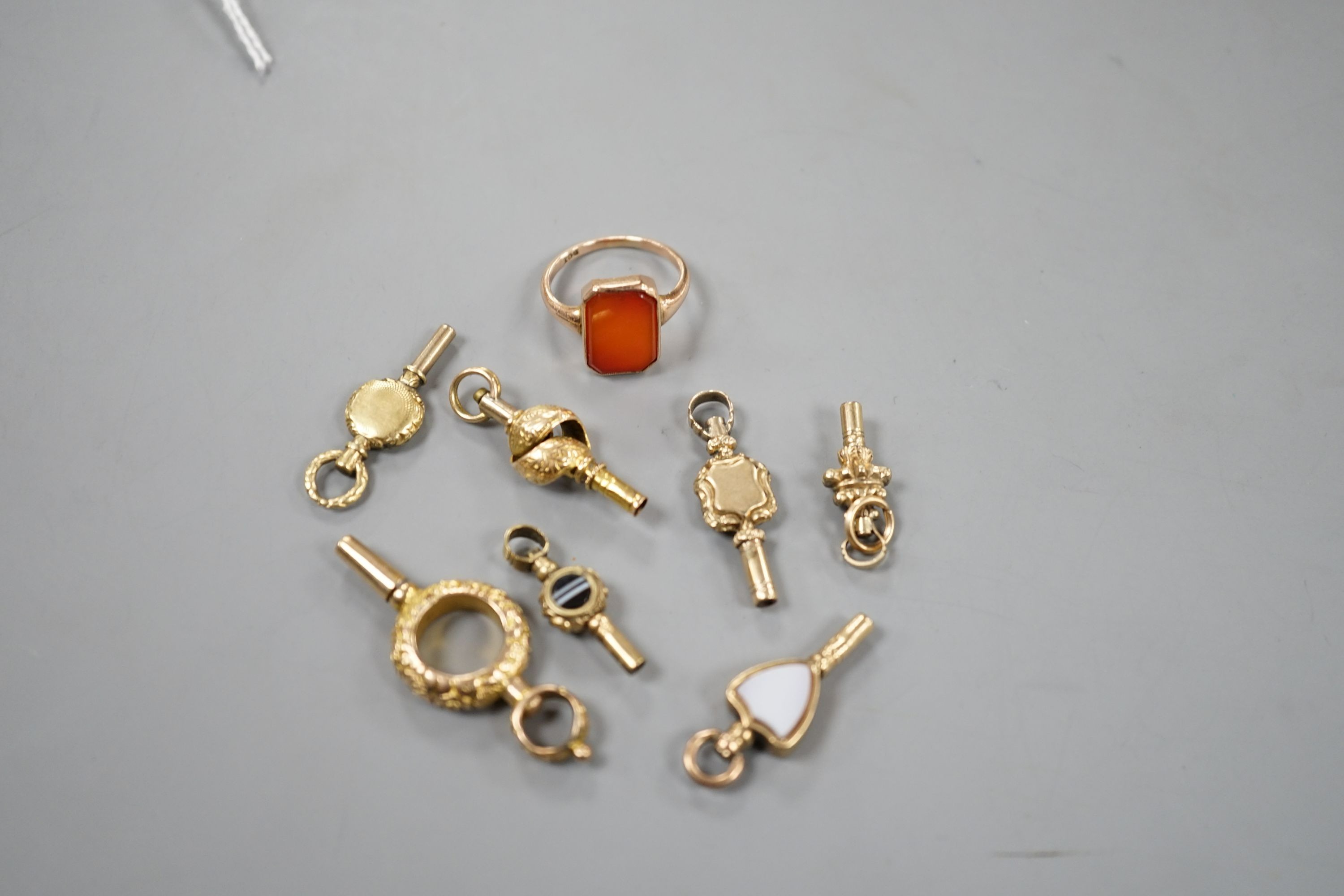 An early 20th century 9ct and carnelian set ring, size K/L, gross 2.7 grams and seven assorted watch keys including three set with chalcedony.